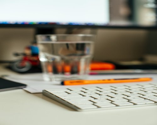 A glass of water and a notebook on a bright desk